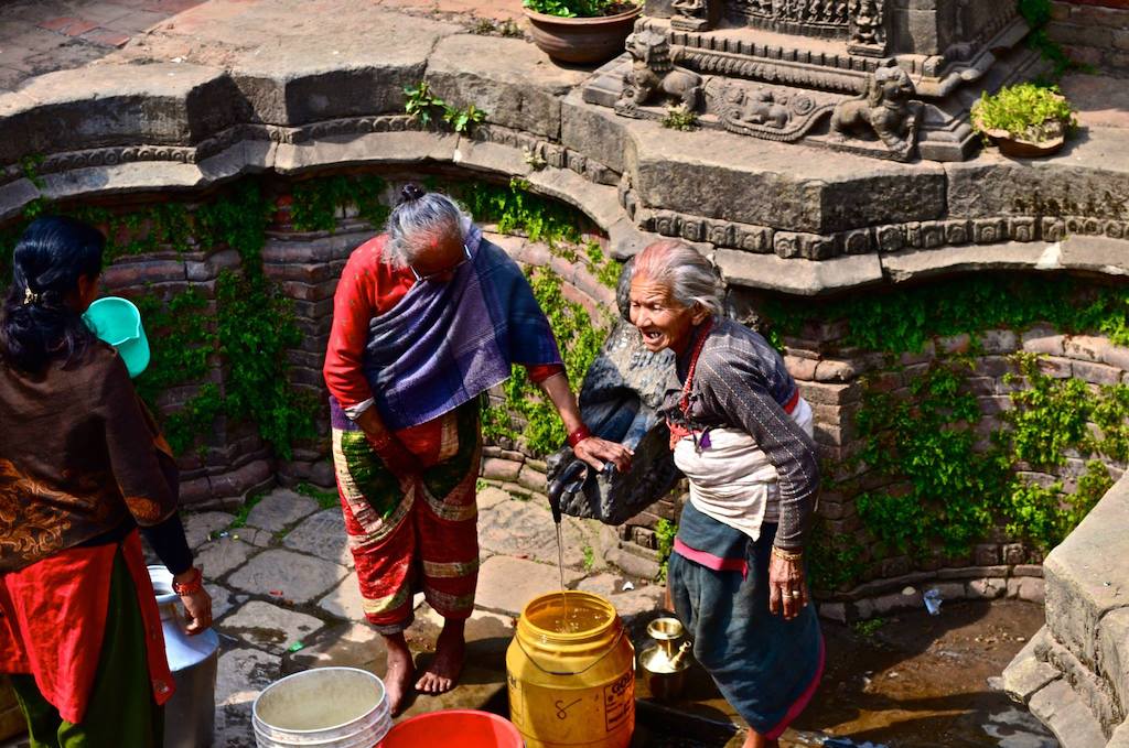 old woman getting water from well